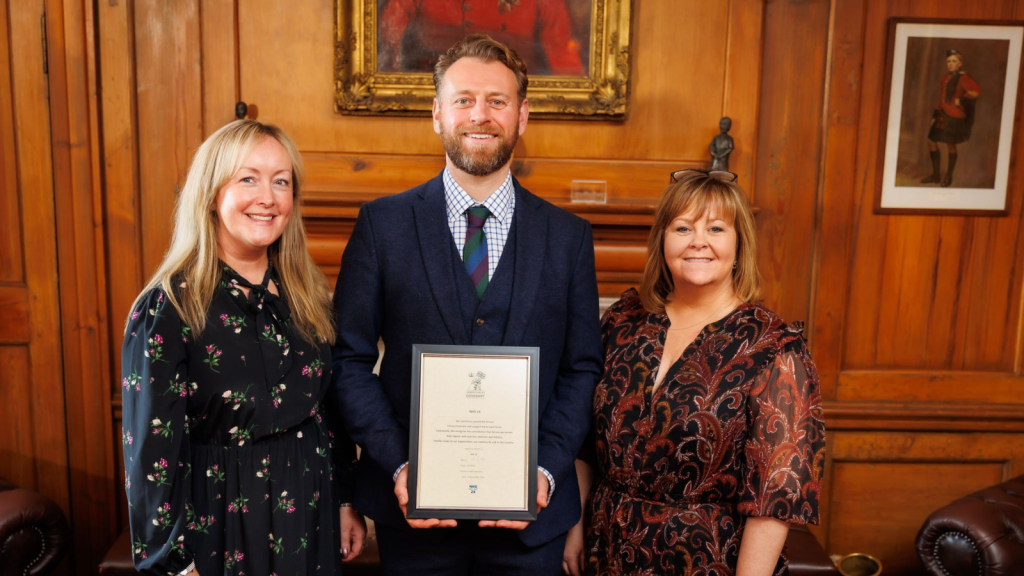 Three people standing with framed certificate
